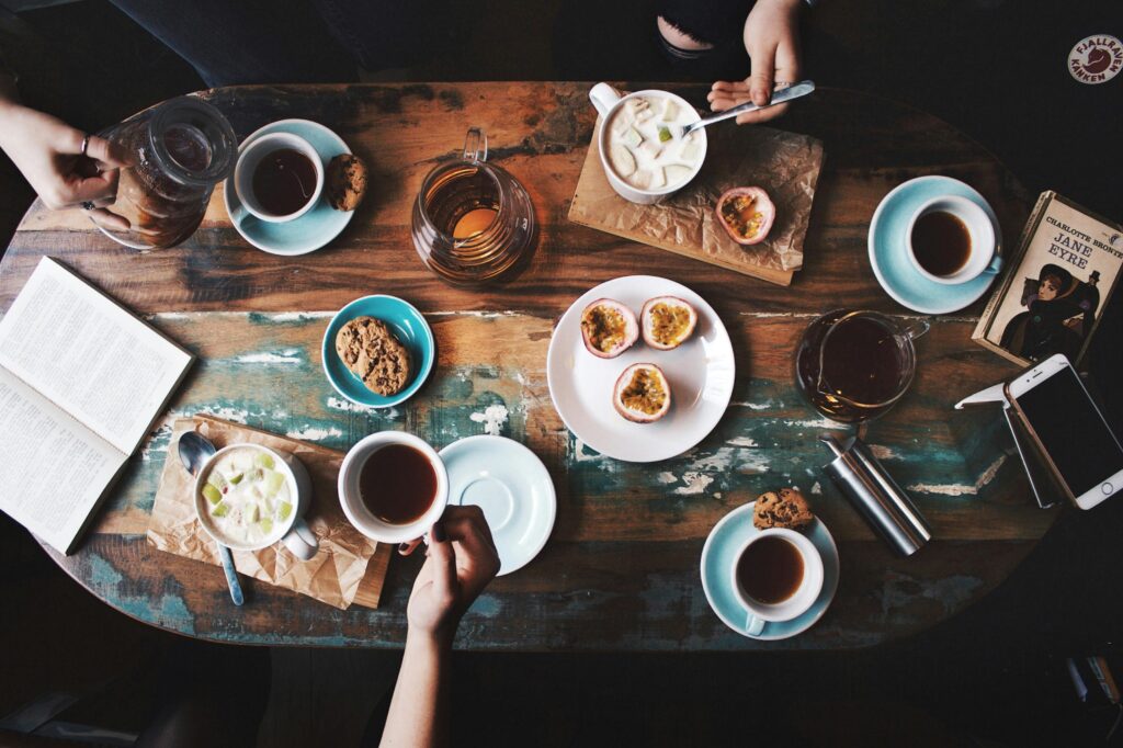 Overhead view of a cozy coffee table setup with cups, snacks, and books, perfect for a relaxing afternoon.