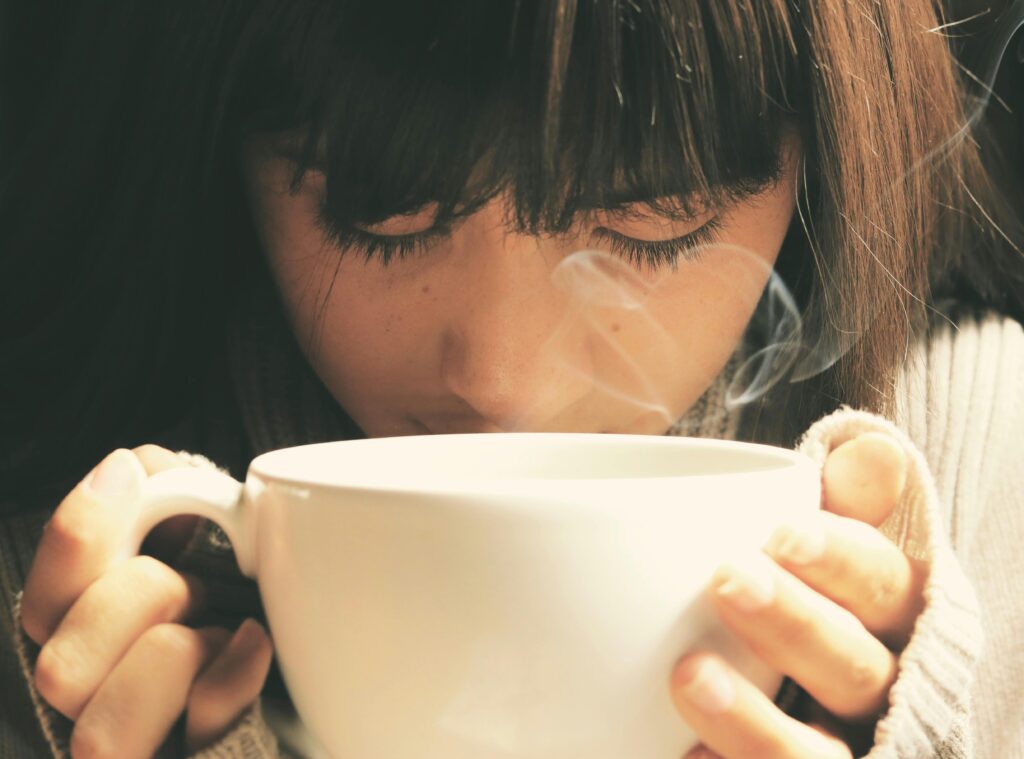 Woman savoring the aroma of a hot coffee cup in a cozy setting.