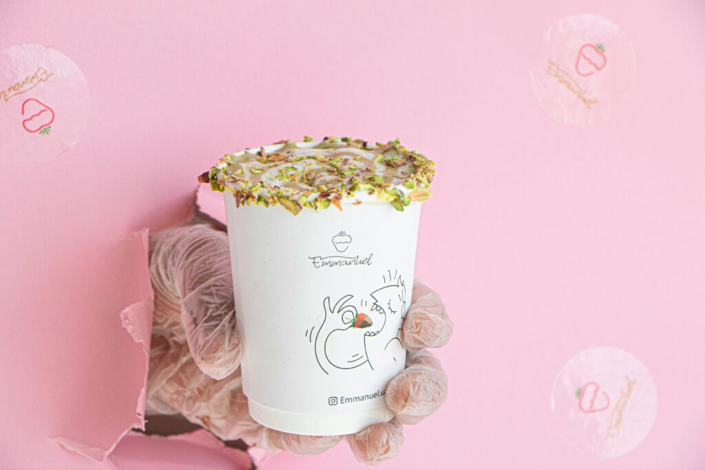 Elegant pink background with a gloved hand holding a decorated cup, featuring unique branding.