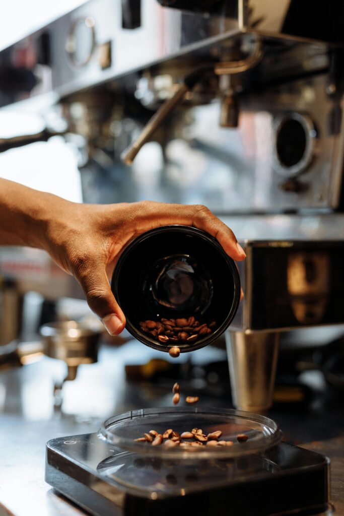 Barista preparing coffee with beans poured into a grinder at a cafe.